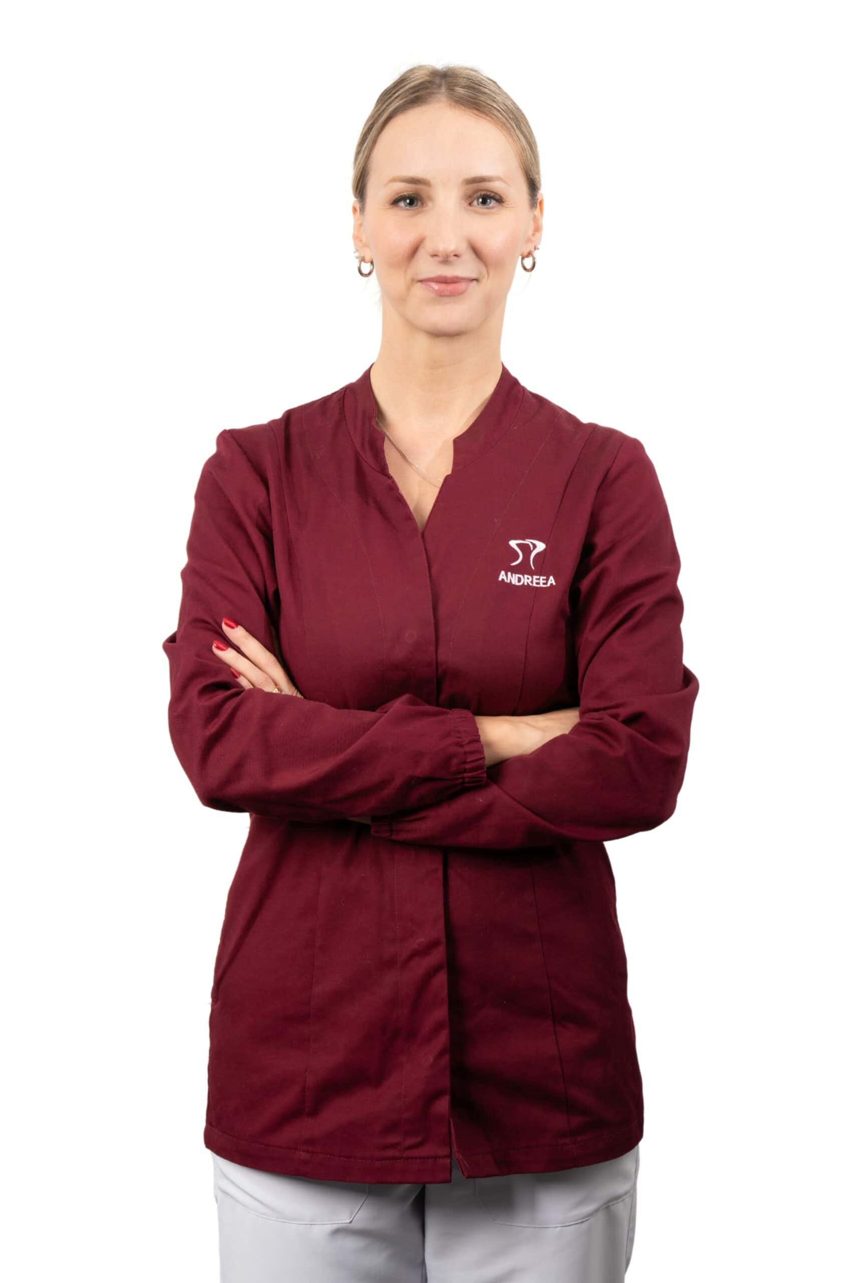 A female healthcare worker in a maroon uniform with crossed arms, standing against a white background, affiliated with Dentalmed Group.